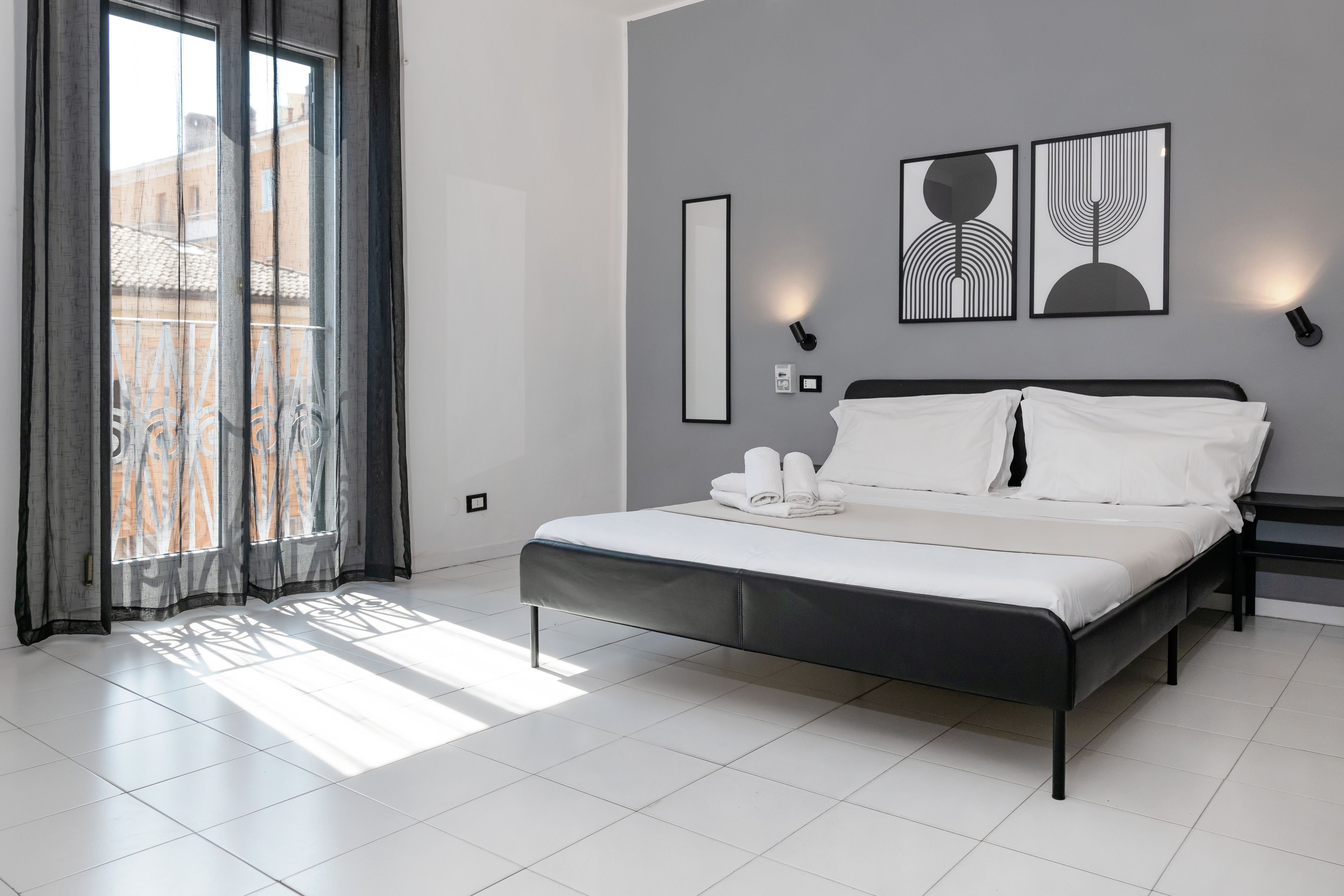 Ein modernes Schlafzimmer mit einem Bett, einem großen Fenster mit Vorhängen und Wandbildern.