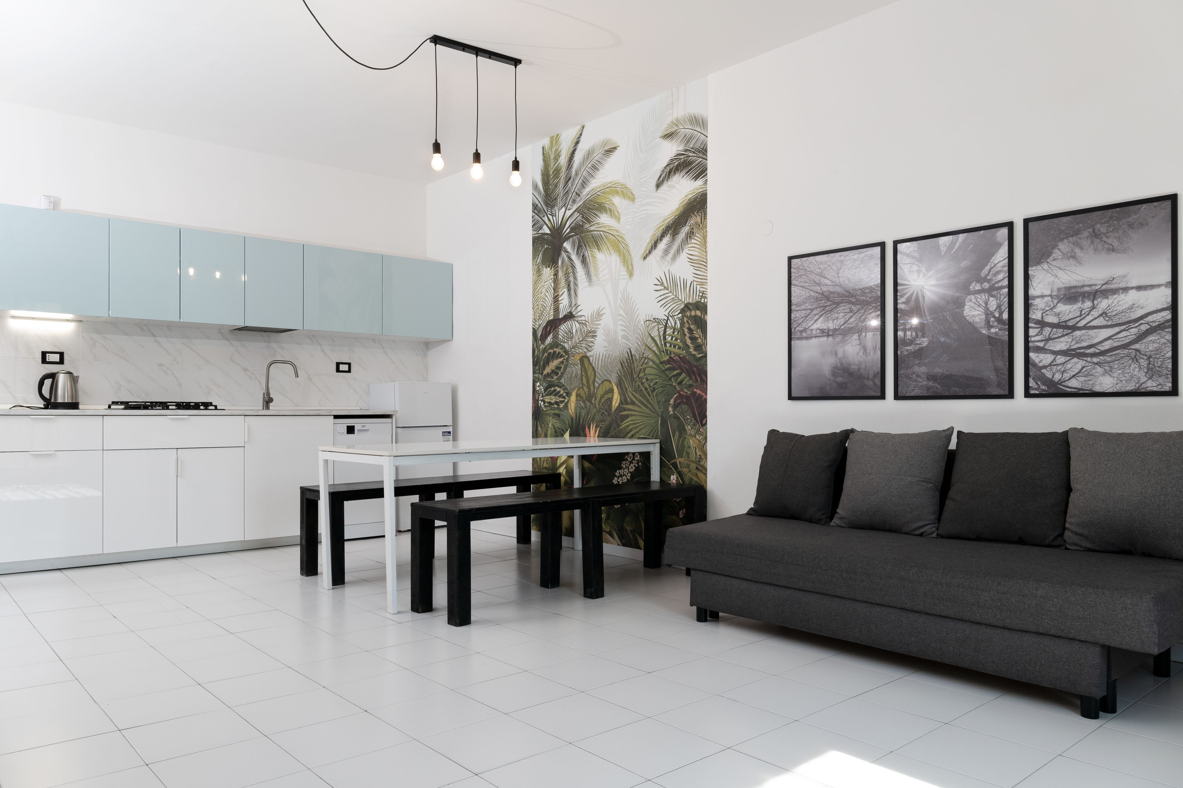 Een moderne keuken met witte kasten, een eettafel en een grijze bank.