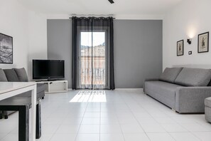 Un salon moderne avec un téléviseur à écran plat, un canapé gris et une table à manger.