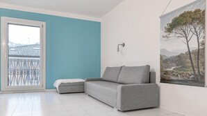 Een moderne woonkamer met een grijze bank, een bijzettafeltje en een schilderij aan de muur.