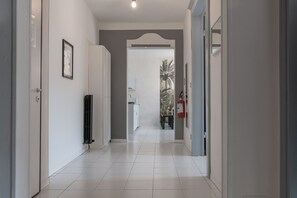 Un couloir aux murs blancs, un tableau encadré, un radiateur et un extincteur.