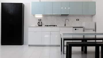 Eine moderne Küche mit weißen Schränken, einem schwarzen Kühlschrank, einem Gasherd und einer Kaffeemaschine.