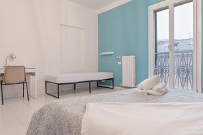 Ein Schlafzimmer mit Bett, Schreibtisch, Stuhl, Bank und Heizkörper.