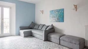 Una sala de estar moderna con un sofá seccional gris, piso estampado y pared azul.