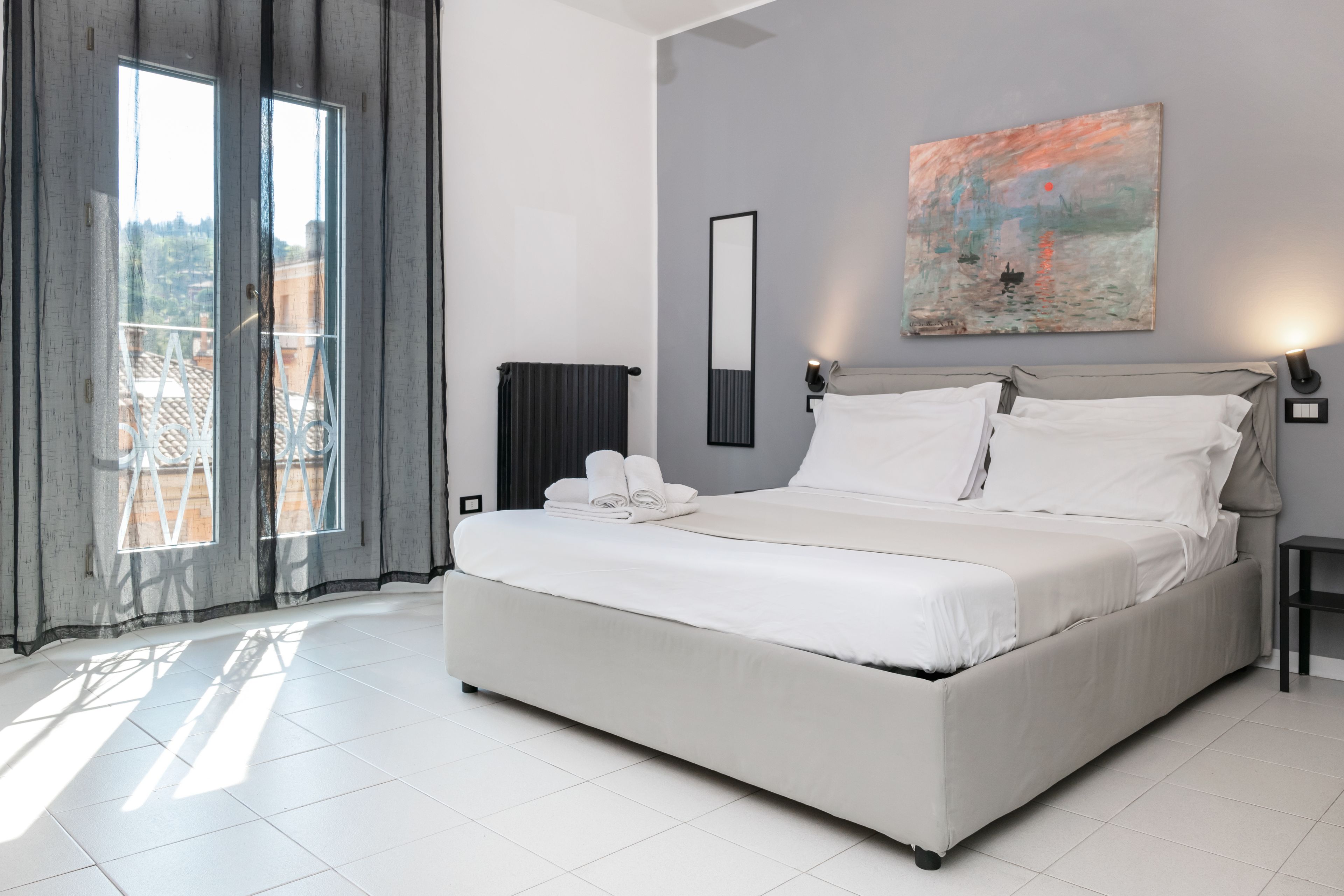 Quarto moderno com uma cama grande, um quadro na parede e vista pela janela.