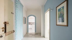 Un pasillo con una puerta de diseño en zigzag, suelo de baldosas y un cuadro enmarcado en la pared.