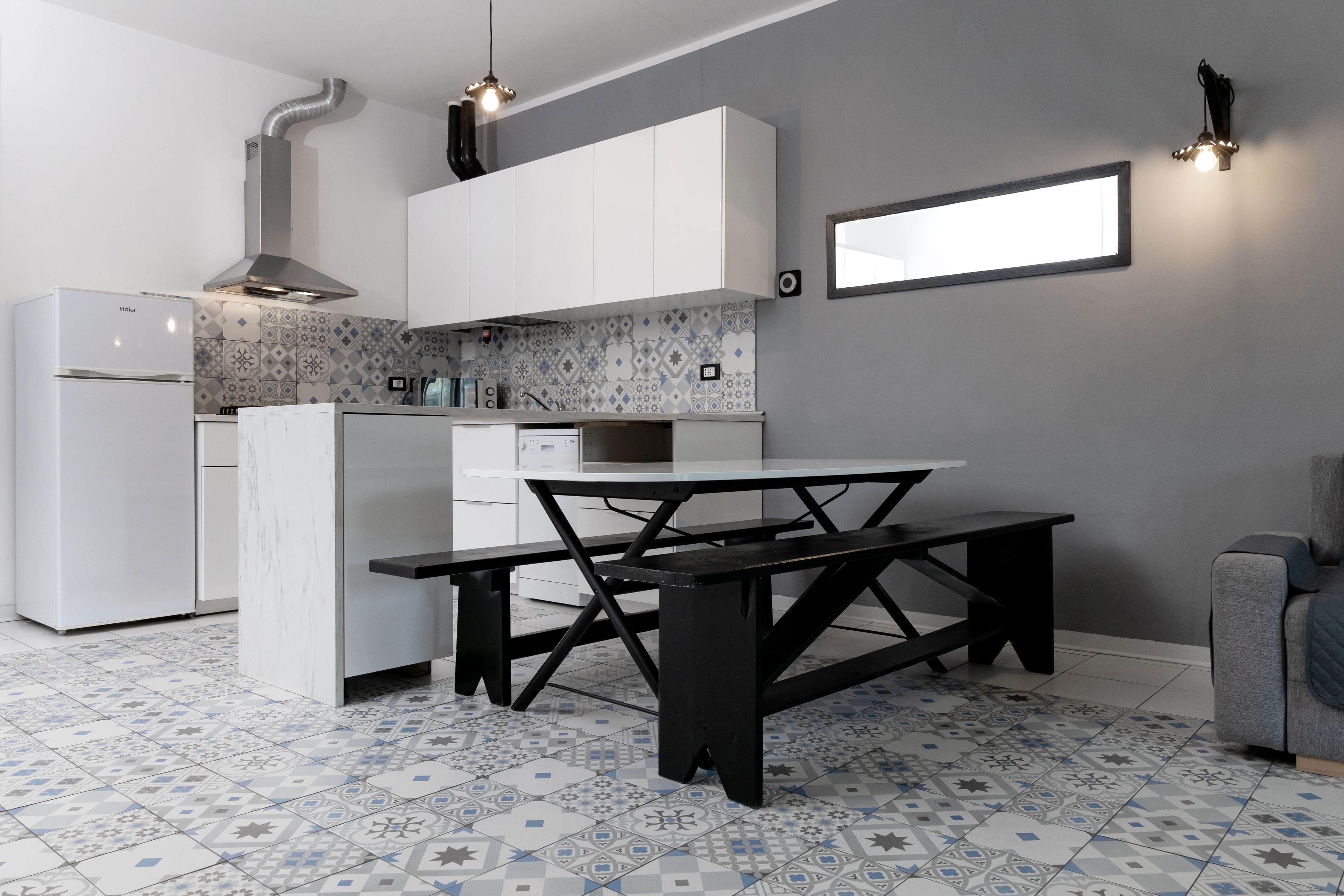 Une cuisine moderne avec des meubles blancs, un îlot central et des carreaux de sol à motifs.