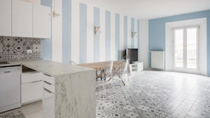 Una cocina moderna con una isla de mármol, pared a rayas y baldosas de suelo con diseño.