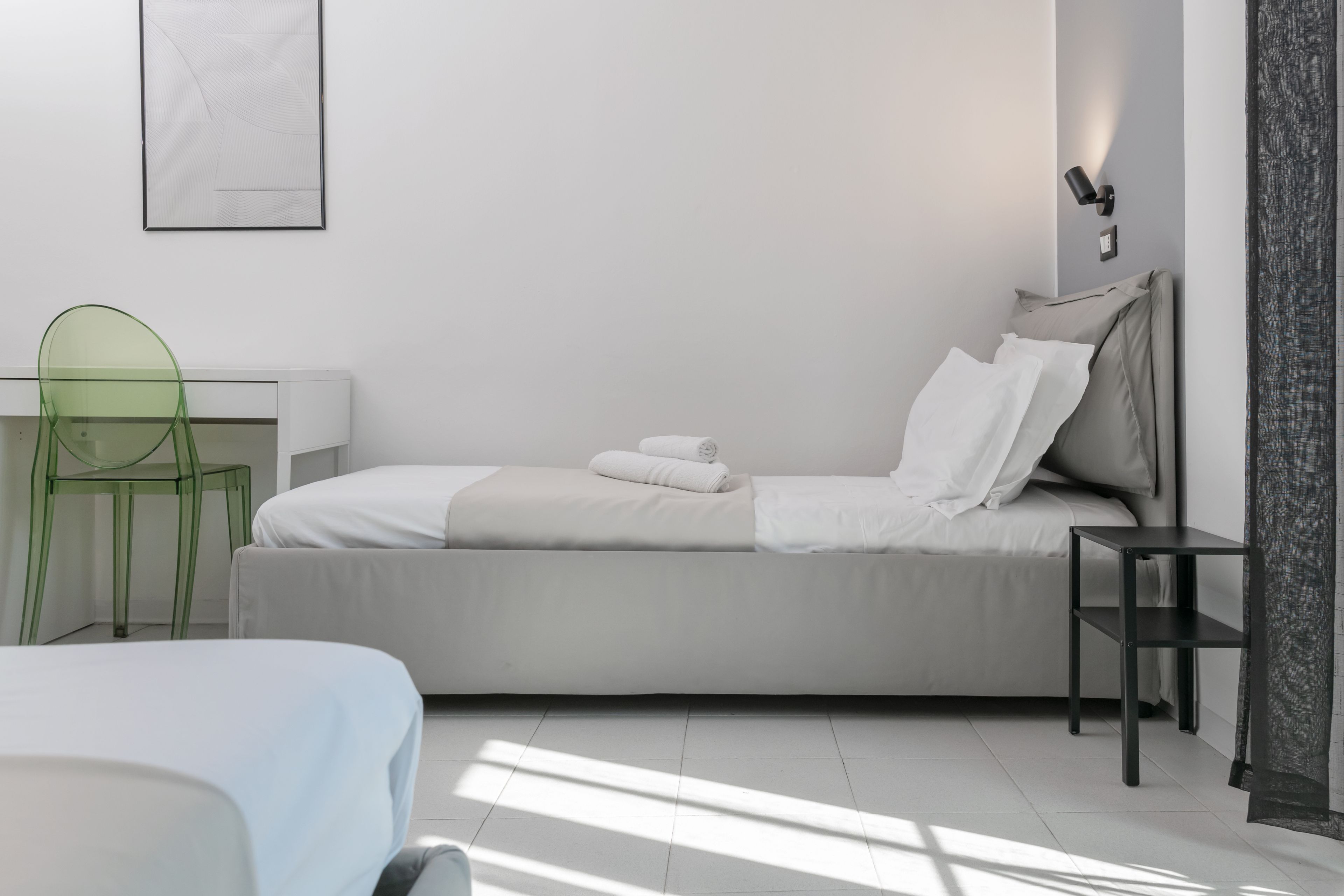 Une chambre à coucher moderne avec un lit, un bureau, une chaise et une table de chevet.