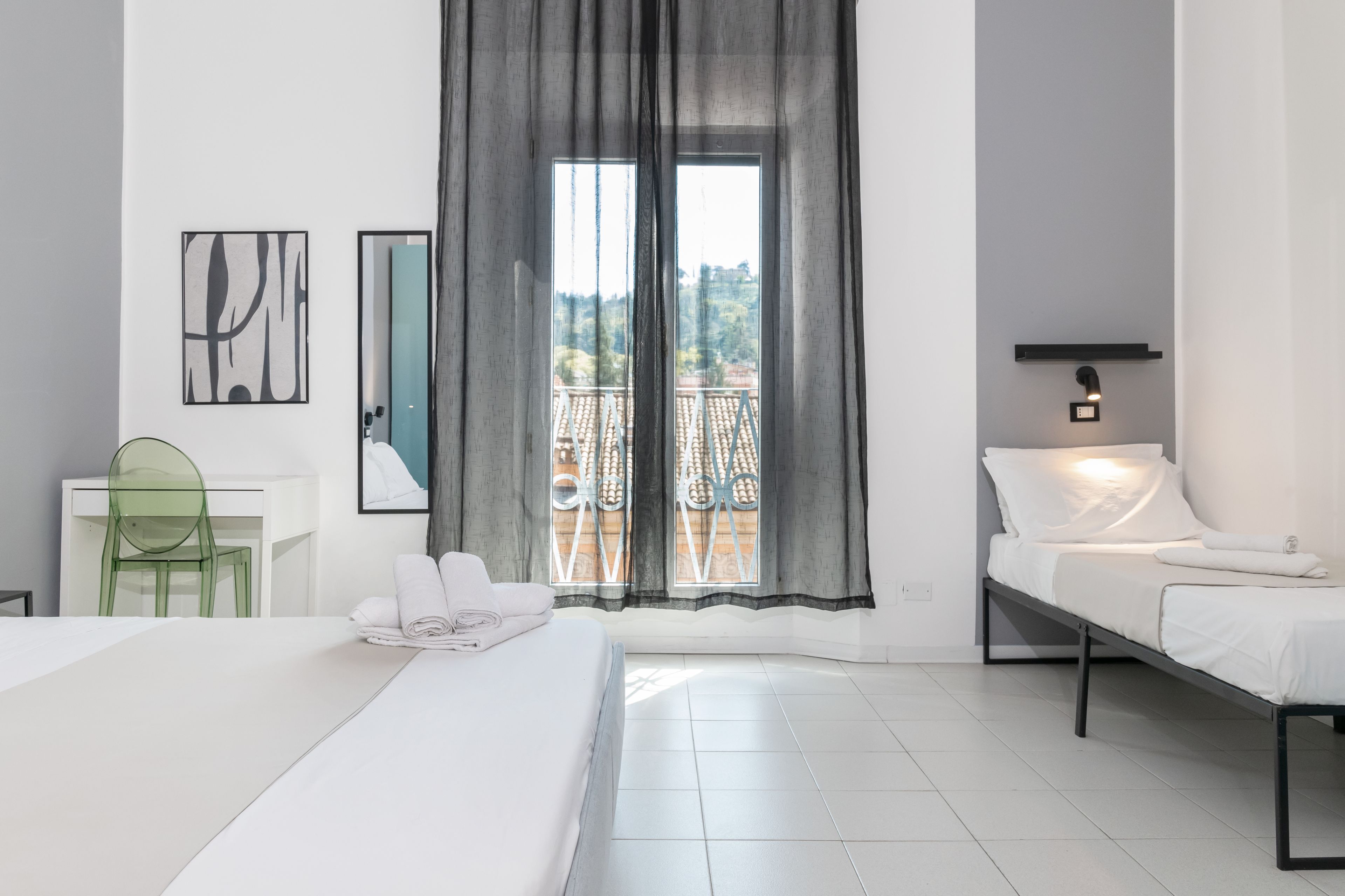Ein Hotelzimmer mit Bett, Schreibtisch, Stuhl, Balkonblick und einer Wandleuchte.