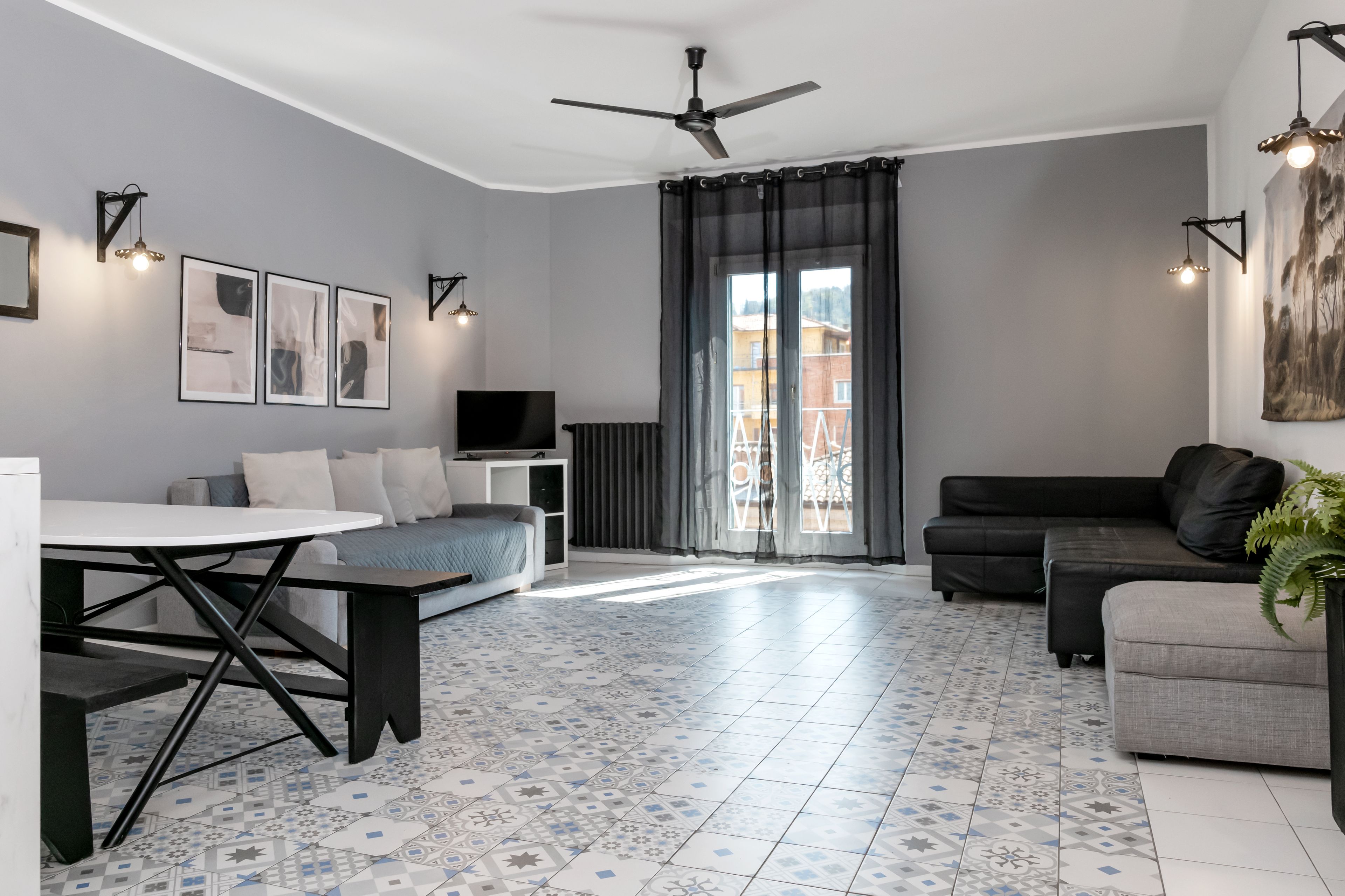 Uma sala de estar moderna com uma mesa de jantar, sofá e ventoinha de teto.