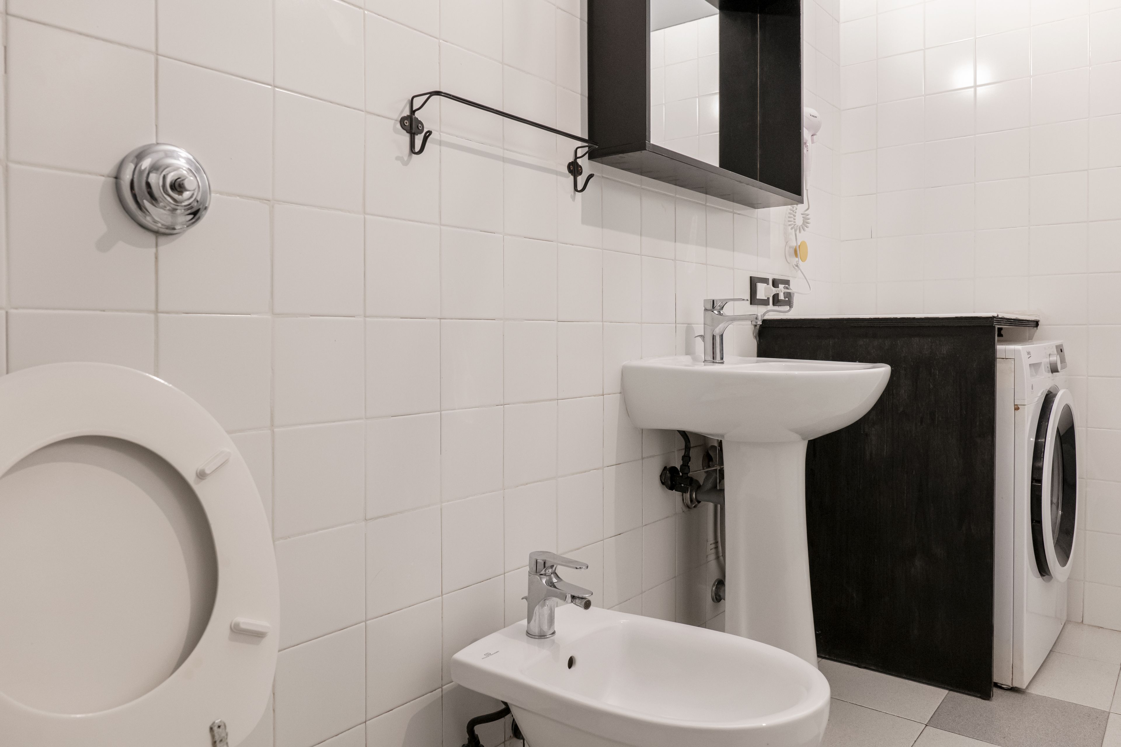 Ein Badezimmer mit Toilette, Waschbecken, Spiegel und Waschmaschine.
