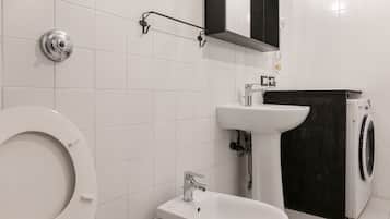 Ein Badezimmer mit Toilette, Waschbecken, Spiegel und Waschmaschine.
