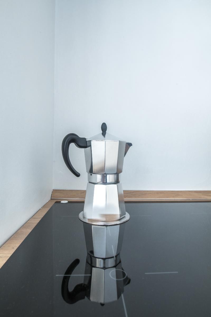 Eine Edelstahl-Kaffeekanne auf einer spiegelnden schwarzen Oberfläche.