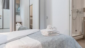 Een moderne hotelkamer met een groot bed, een douchecabine van glas en uitzicht op de badkamer.