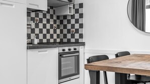 Een moderne keuken met een zwart-wit geruit spatwand, een fornuis en een oven. Er is een eettafel met stoelen.