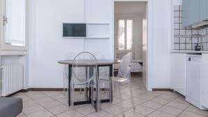 Een moderne keuken met witte kastjes, een inbouwoven en een betegelde spatwand.