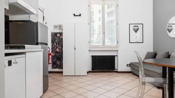 A compact kitchen with a refrigerator, stove, and a dining area with a table and chairs.