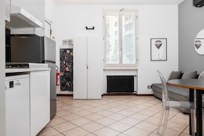Una cocina compacta con refrigerador, estufa y comedor con mesa y sillas.