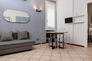Una sala de estar moderna con un sofá gris, una mesa redonda y sillas transparentes.