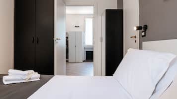 A hotel room with a bed, a wardrobe, and a view into the hallway.
