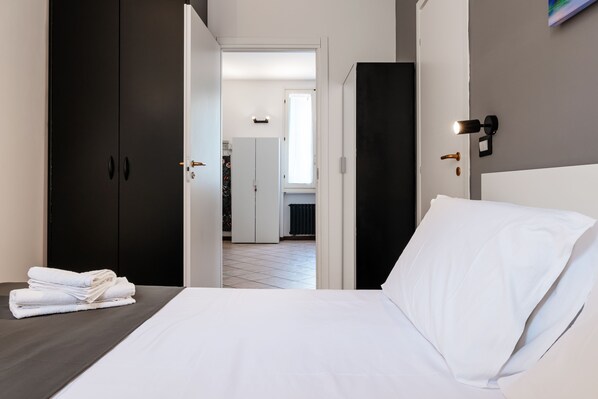Una habitación de hotel con cama, armario y vistas al pasillo.