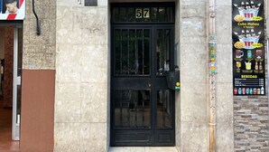 Eine schwarze Tür mit der Nummer 57, ein Friseurschild und ein Menüposter an der Wand.