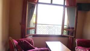 Una habitació amb una finestra gran, dues cadires i una taula petita.