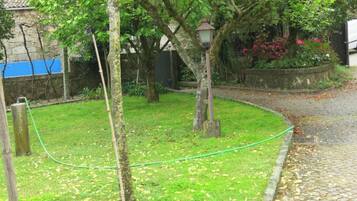 A garden with a paved path, a lamp post, and a stone wall.