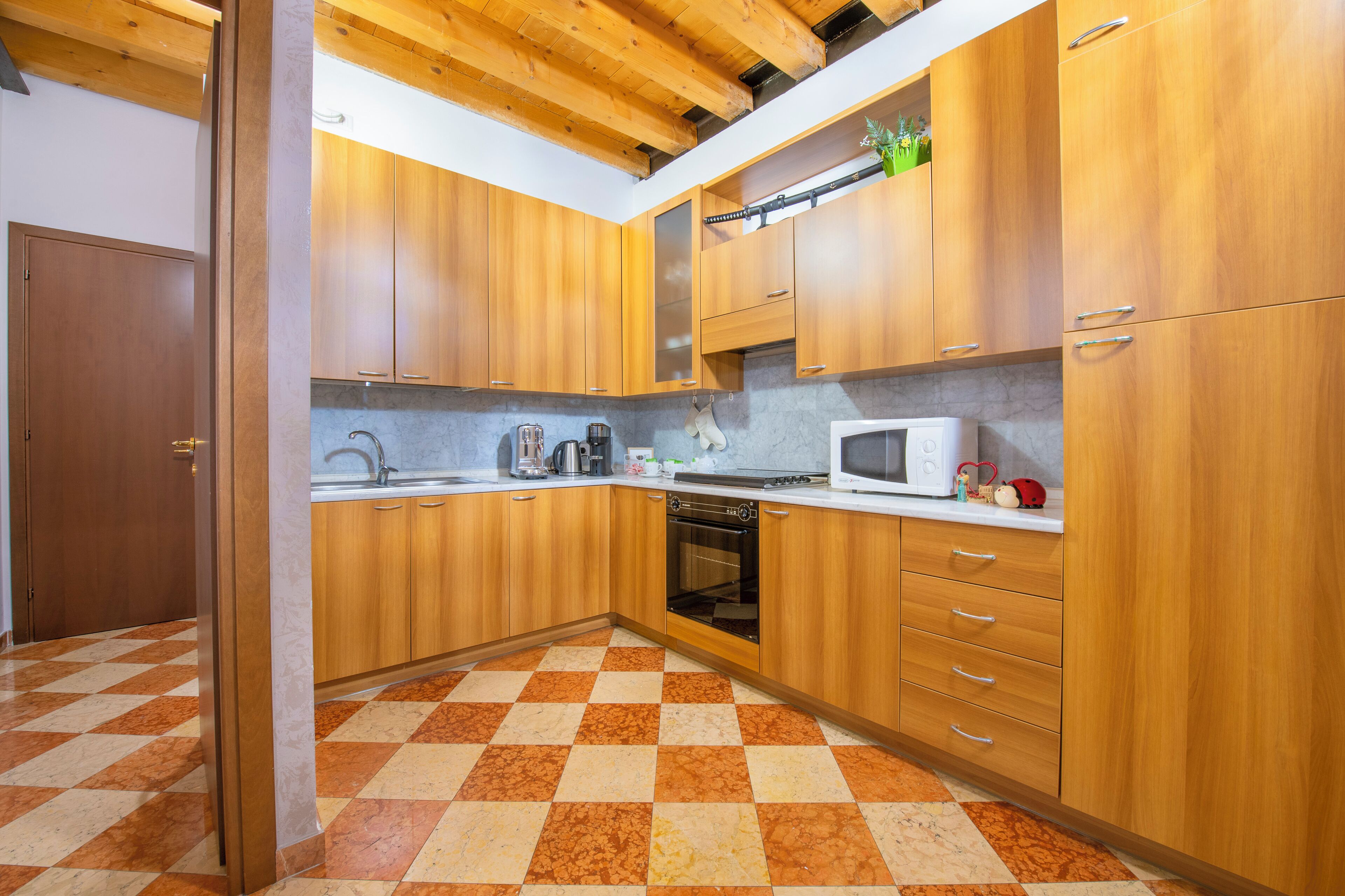Une cuisine avec des meubles en bois, un four à micro-ondes et un sol à carreaux.