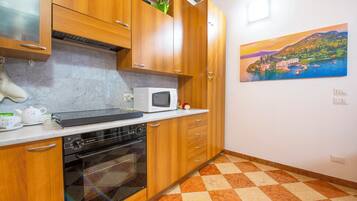 A kitchen with wooden cabinets, a microwave, and a painting of a coastal scene.