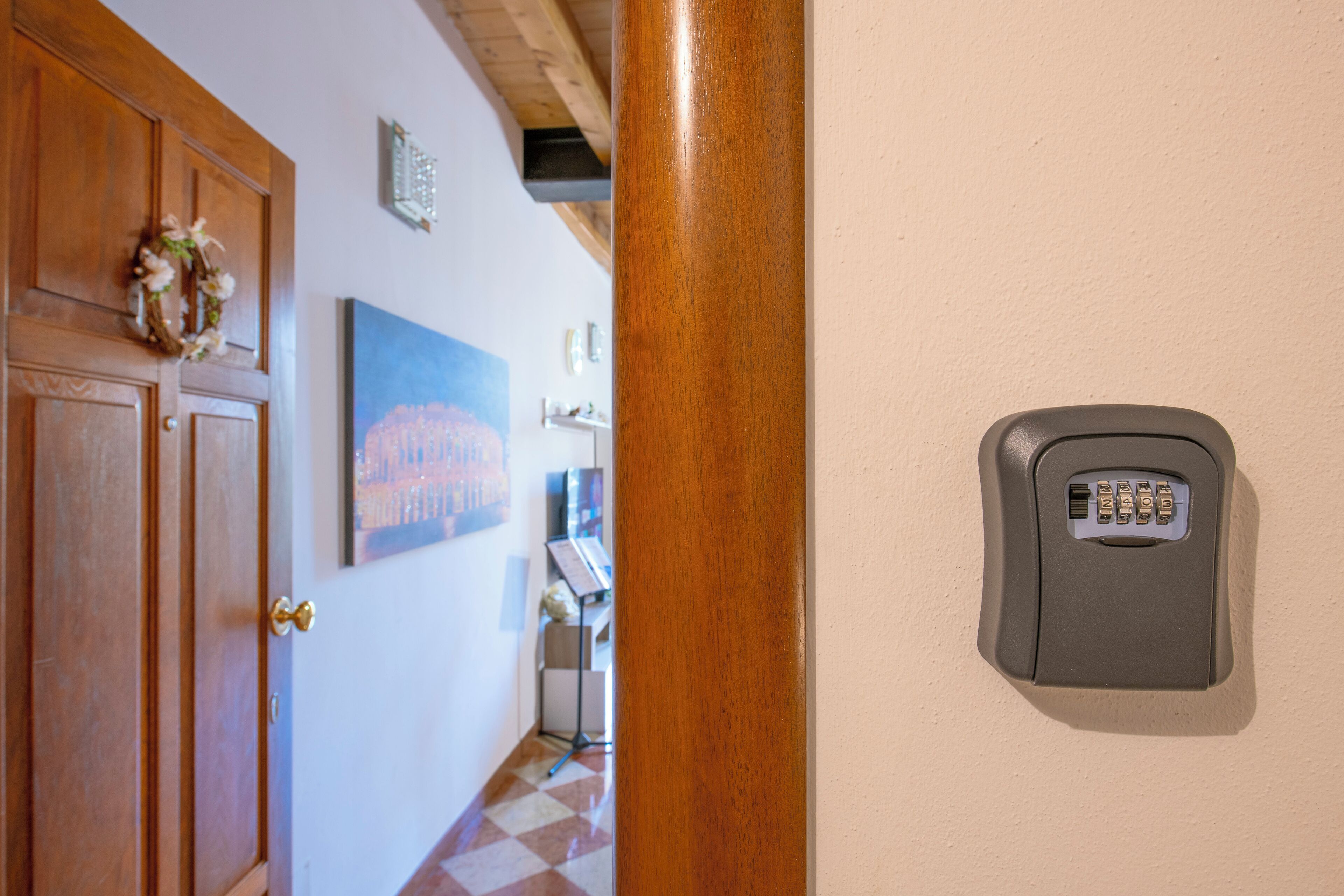 A door with a keypad lock, a wooden door frame, and a wall-mounted picture.