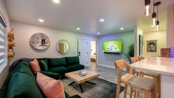 Una sala de estar moderna con un sofá verde, una mesa de centro de madera y un televisor montado en la pared.