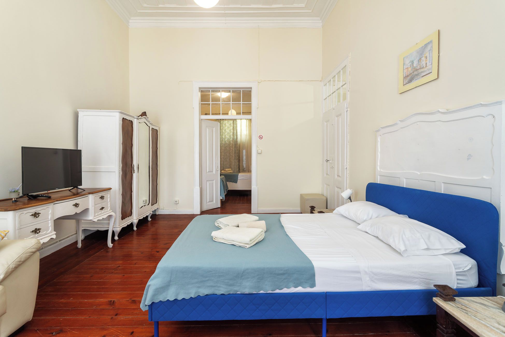 Una habitación de hotel con una cama, televisión, armario y escritorio.