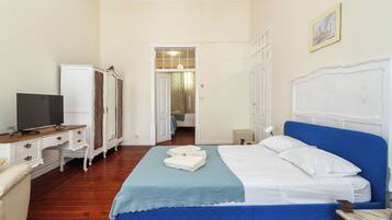 Una habitación de hotel con una cama, televisión, armario y escritorio.