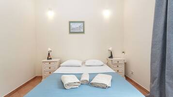 Habitación de hotel con cama, dos mesitas de noche, una lámpara de noche, un cuadro en la pared y una ventana con cortinas.