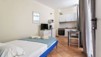 Une chambre d’hôtel comprenant un lit, un bureau avec un ordinateur, une kitchenette et une salle de bain.