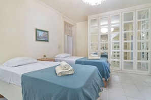 Habitación de hotel con dos camas, un amplio ventanal corredero y un cuadro en la pared.