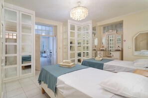 Habitació d'hotel amb dos llits, una pèndol, un armari i un bany visible a través d'una porta oberta.