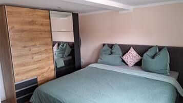 A bedroom with a bed, a wardrobe, and a mirror.