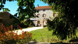 A stone building with a tiled roof, a paved driveway, and a lawn. - Spacious suite with wellness, parking, wifi, in Saint-Privat-d'Allier (Saint-Privat-d'Allier)