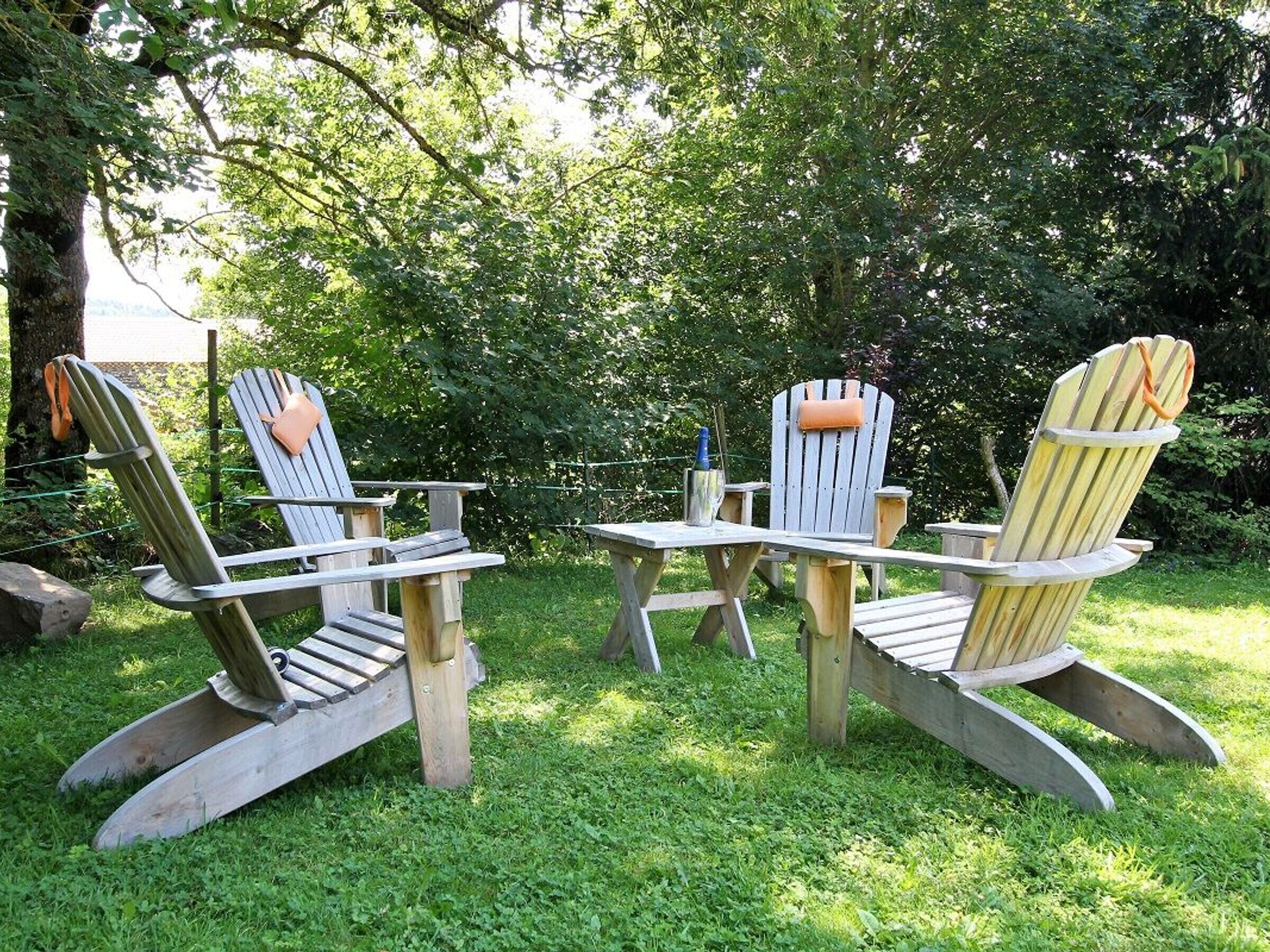 Deux fauteuils Adirondack avec des bancs intégrés, une petite table et une bouteille d’eau, le tout installé dans un jardin.