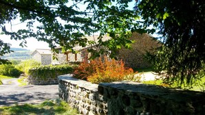 A stone wall with a stone building partially obscured by foliage. - Spacious suite with wellness, parking, wifi, in Saint-Privat-d'Allier (Saint-Privat-d'Allier)