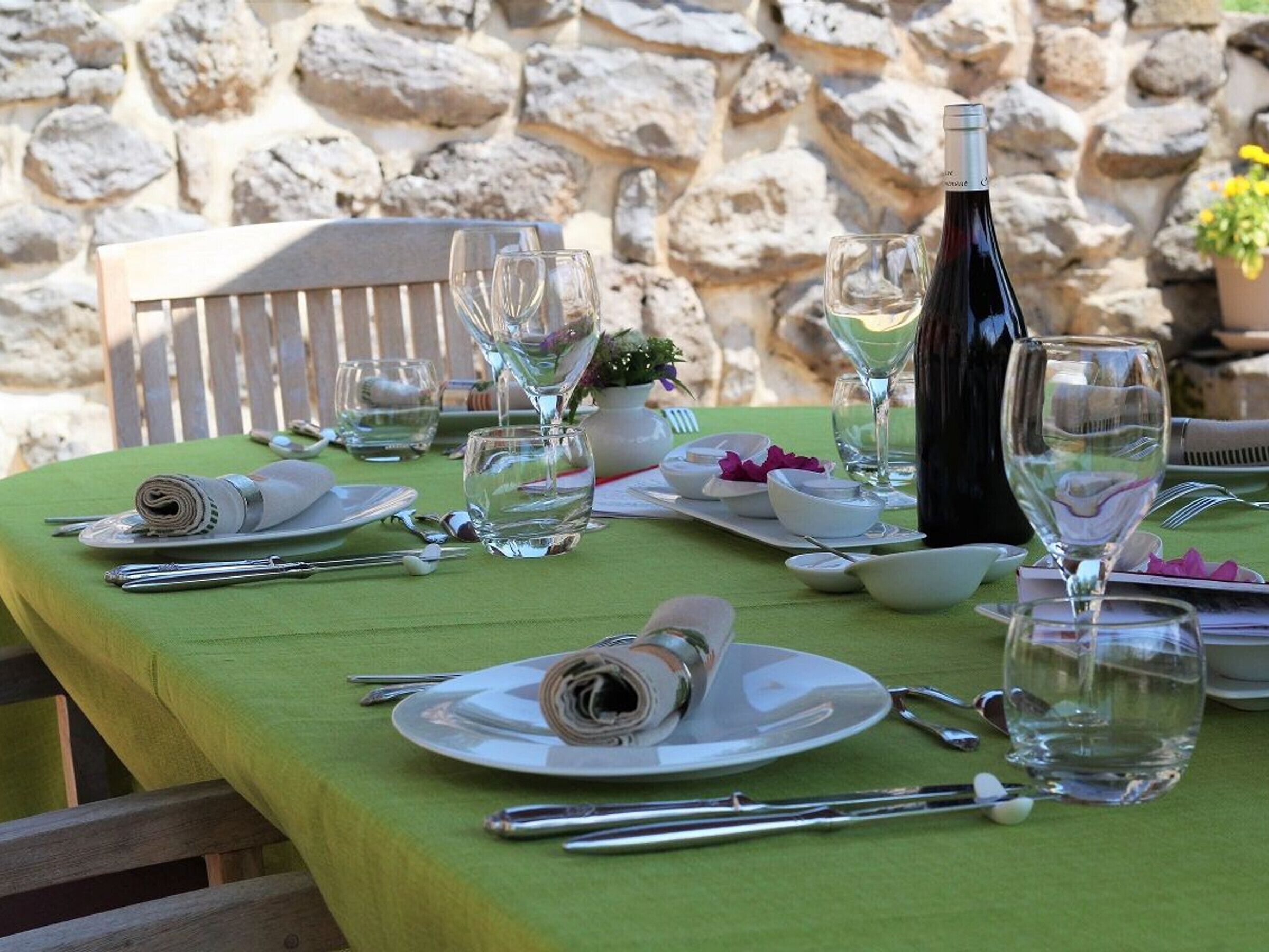 A table set for a meal with a bottle of wine, clear glasses, and neatly folded napkins.