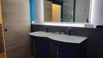 Une salle de bain moderne avec un double vasque, un grand miroir et une porte en bois.