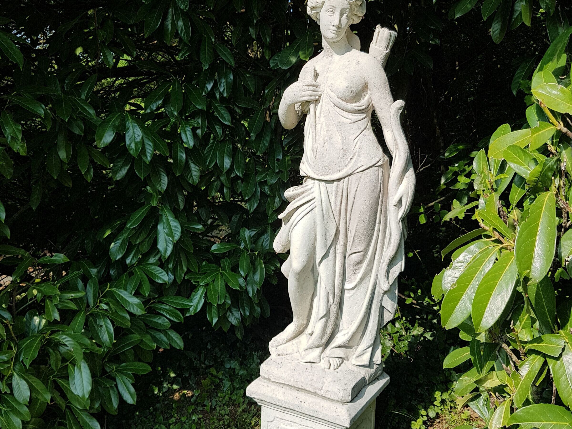 Una estatua de mujer en un jardín.