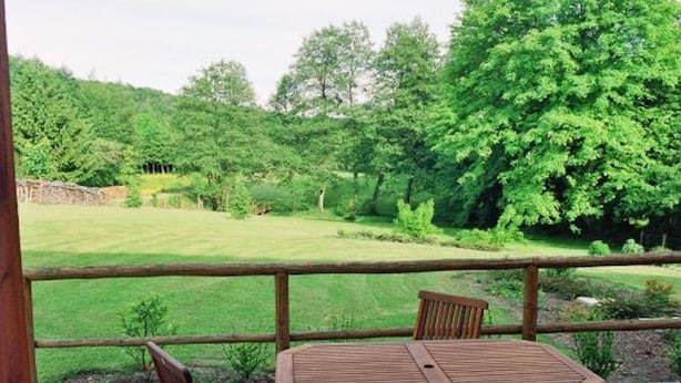 A wooden deck with a table and chairs, overlooking a grassy yard with trees. - Charming Accessible Yemeni Suite in the Heart of Argonne (Futeau)