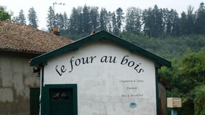 A rustic building with a sign reading "le four au bois" indicating it is a bed and breakfast. - Charming Accessible Yemeni Suite in the Heart of Argonne (Futeau)