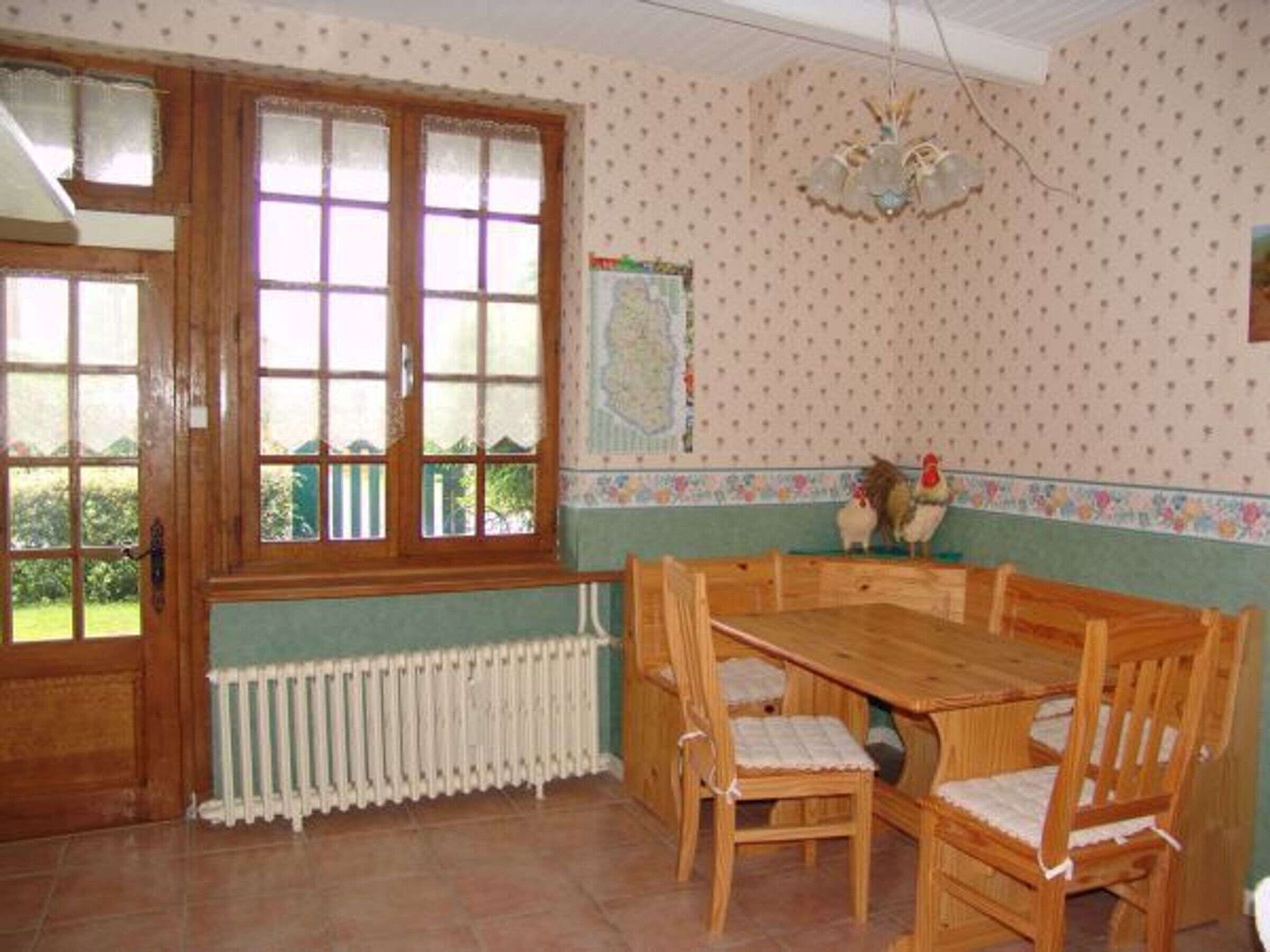 Un coin repas avec une table et des chaises en bois, un radiateur placé sous une fenêtre et un mur orné d’un motif à pois.