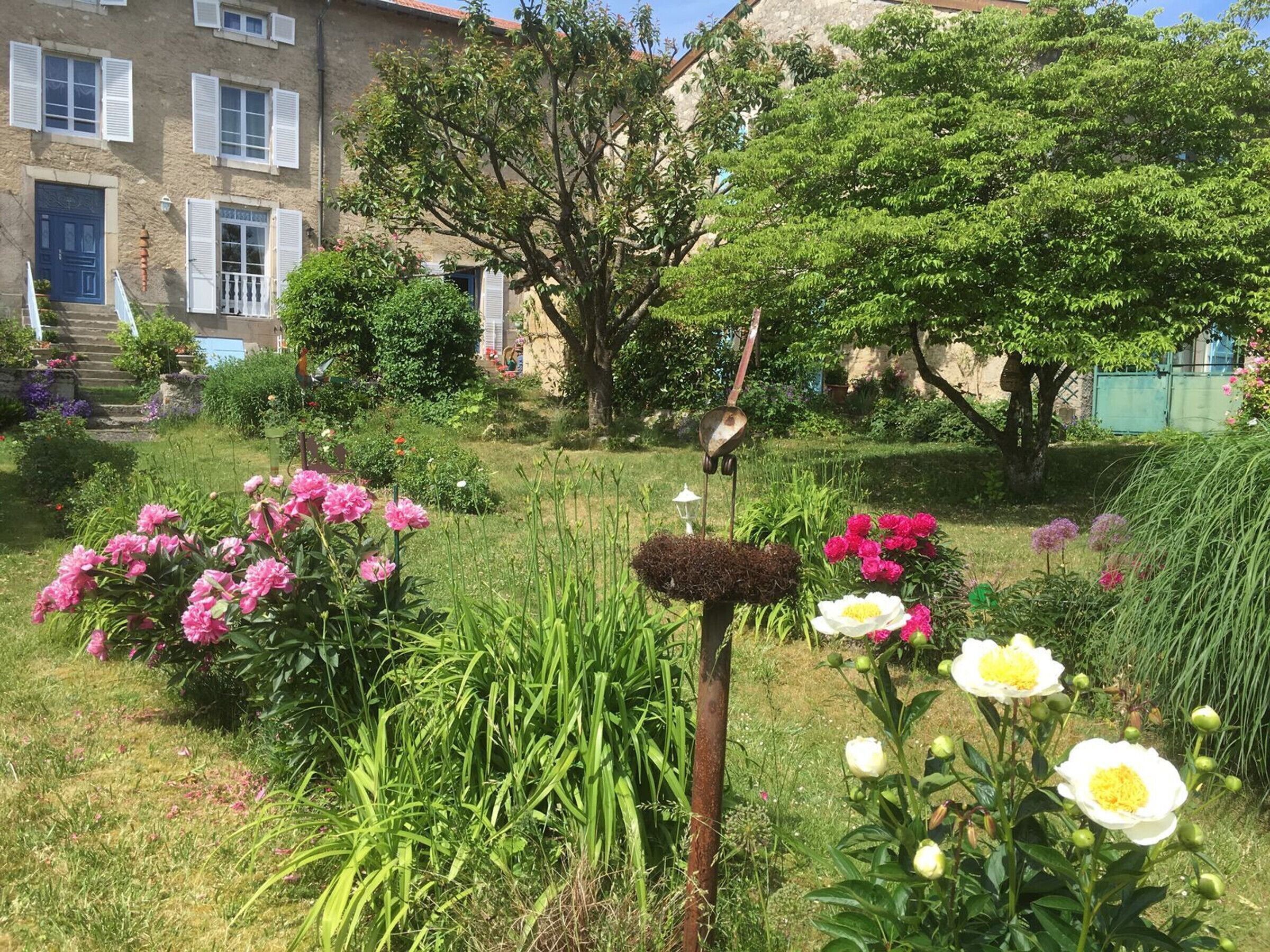 Um jardim com diversas flores e um edifício rústico com degraus que levam a uma porta.
